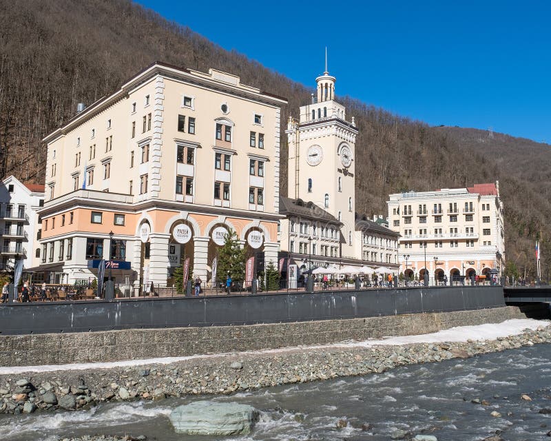 Ski resort Rosa Khutor., Russia. A view of the Mzymta River and town hall with clock on Rosa Square. Cityscape stock images